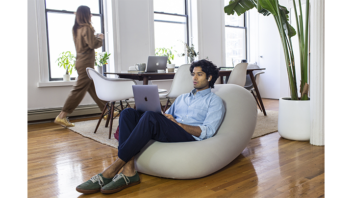 adult man sitting and working on laptop on moon pod in seated position